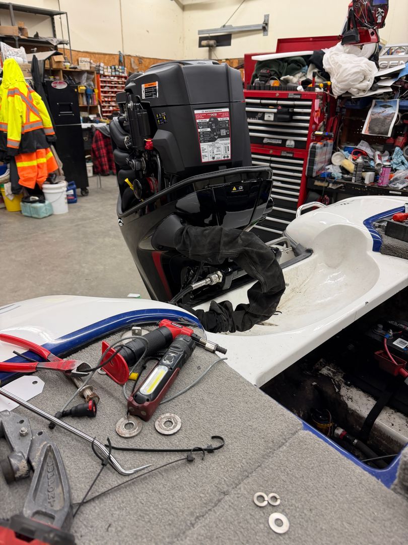 The replacement Mercury 115 Pro XS with its cowl removed during installation on a bass boat in the Harris Boat Works workshop.